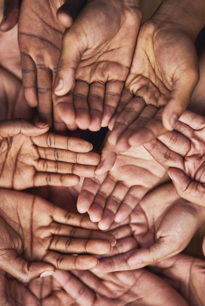 Seeking your help. Shot of a group of hands held cupped out together.